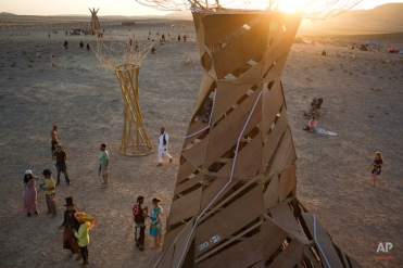 In this photo taken Friday, June 6, 2014, people, mostly Israelis, walk in the playa during Israel's first Midburn festival, modeled after the popular Burning Man festival held annually in the Black Rock Desert of Nevada, in the desert near the Israeli kibbutz of Sde Boker. Some 3,000 people set up a colorful encampment in the dusty moonscape, swinging from hoops by day and burning giant wooden sculptures by night. At the end, participants were told to remove their own trash and leave the desert without a trace.(AP Photo/Oded Balilty)