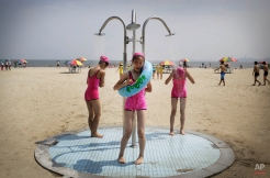 North Korean girls in similar bathing suits stand under a shower at the Songdowon International Children's Camp, Tuesday, July 29, 2014, in Wonsan, North Korea. The camp, which has been operating for nearly 30 years, was originally intended mainly to deepen relations with friendly countries in the Communist or non-aligned world. But officials say they are willing to accept youth from anywhere - even the United States. (AP Photo/Wong Maye-E) License this photo
