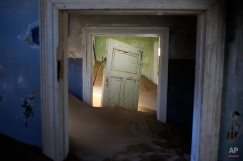In this July 23, 2013 photo, sand fills an abandoned house in Kolmanskop, Namibia. Kolmanskop, was a diamond mining town south of Namibia, build in 1908 and deserted in 1956. SInce then, the desert slowly reclaims its territory, with sand invading the buildings where 350 German colonists and more than 800 local workers lived during its hay-days of the 1920s. (AP Photo/Jerome Delay)