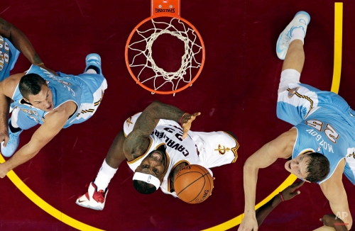 Cleveland Cavaliers' LeBron James, center, jumps to the basket against Denver Nuggets' Danilo Gallinari, left, of Italy, and Denver Nuggets' Timofey Mozgov, of Russia, in the second half of an NBA basketball game Monday, Nov. 17, 2014, in Cleveland. The Nuggets defeated the Cavaliers 106-97. (AP Photo/Tony Dejak)