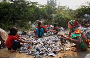 In this Nov. 11, 2014 photo, Marjina, right, segregates trash with the help of her children and a young neighbor outside their rented shanty on the outskirts of New Delhi, India. (AP Photo/Altaf Qadri)