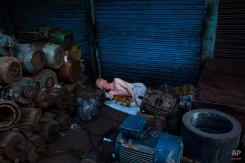 An albino man sleeps surrounded by piles of equipment in New Delhi, India, Tuesday, Aug. 26, 2014. Many laborers in the Indian capital have no permanent residence and are forced to sleep in the streets. (AP Photo/Bernat Armangue)