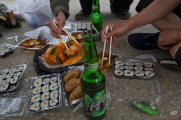 In this June 16, 2014 photo, North Korean men share a picnic lunch and North Korean-brewed and bottled Taedonggang beer along the road in North Korea's North Hwanghae province. (AP Photo/David Guttenfelder)