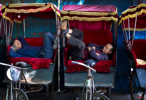 Chinese trishaw drivers take nap while waiting for customers at a hutong alley near the drum tower, a tourist spot in Beijing, China Wednesday, May 7, 2014. (AP Photo/Andy Wong)