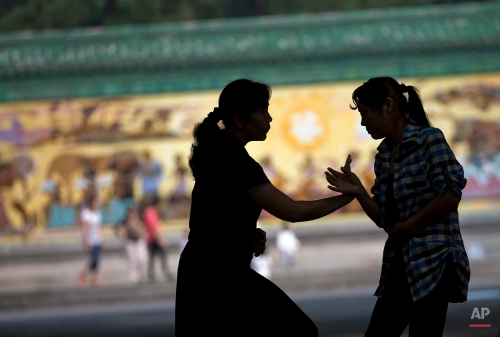 Chinese women practice a pushing hands, known as "Tuishou," part of a Chinese Taichi martial art technique, in the morning exercise at Ritan Park in Beijing Monday, Sept. 9, 2013. (AP Photo/Andy Wong)