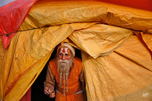 An Indian Hindu Holy man carries a glass as he walks out of his tent to perform a ritual ahead of the annual month long Hindu religious fair "Magh Mela" in Allahabad, India, Sunday, Jan. 4, 2015. Hundreds of thousands of devout Hindus camp and take a bath at the confluence during the astronomically auspicious period of over 45 days that begins on Jan. 5, hoping to rid themselves of their sins and attain prosperity. (AP Photo/Rajesh Kumar Singh)