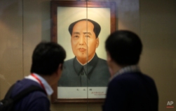 Visitors look at the portrait of former Chinese leader Mao Zedong in Shanghai, China, Monday, July 29, 2013. (AP Photo/Eugene Hoshiko)
