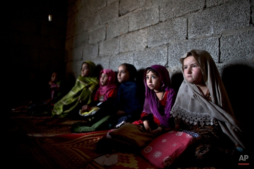 Afghan refugees and internally displaced Pakistani girls from tribal areas sit on the ground during a class on how to read and write at a makeshift school on the outskirts of Islamabad, Pakistan, Tuesday, Feb. 17, 2015. (AP Photo/Muhammed Muheisen)
