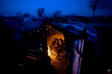 Pakistani Sughar Ramadan, 38, and her daughters Shameem, 7 and Samreen, 2, sit around a fire to warm themselves from the night cold inside their makeshift home in a slum in Islamabad, Pakistan, Friday, Feb. 13, 2015. (AP Photo/Muhammed Muheisen)