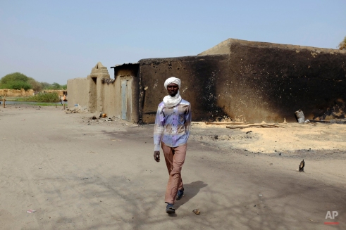 A man walks past a a house bearing burn marks in the Lake Chad shore village of N'Gouboua Thursday March 5, 2015. Boko Haram militants arrived in Nígouboua before dawn on Feb. 13, marking the first attack of its kind on Chad. By the time the scorched-earth attack ended, they had burned scores of mud-brick houses by torching them with gasoline and had killed at least eight civilians and two security officers. Some 3,400 Nigerian refugees had been living in te village at the time of the attack, and all have since been relocated further inland. (AP Photo/Jerome Delay)