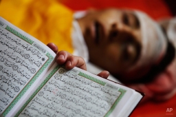 A mourner reads from the Quran, Islam's holy book, next to the body of Palestinian militant Ibrahim Al-Wahidi, 25, at a Gaza City mosque, prior to his funeral procession, Monday, June 7, 2010. Al-Wahidi along with 3 other comrades in diver suits from the Al-Aqsa Martyrs' Brigades, the remnants of a violent offshoot of Palestinian President Mahmoud Abbas' Fatah faction, were killed by Israeli forces in the waters off Gaza. (AP Photo/Lefteris Pitarakis)