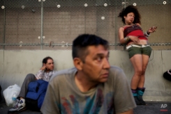 George Mendez, foreground, a 55-year-old recovering alcoholic, sits in front of a drunk woman in the Skid Row area of Los Angeles on July 23, 2013. The area, originally agricultural until the 1870s when railroads first entered Los Angeles, has maintained a transient nature through the years from the influxes of short-term workers, migrants fleeing economic hardship during the Great Depression, military personnel during World War II and the Vietnam conflict, and low-skilled workers with limited transportation options who need to remain close to the city's core, according to the Los Angeles Chamber of Commerce. (AP Photo/Jae C. Hong)