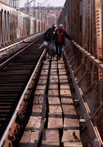 In this Saturday, Feb. 28, 2015 photo Migrants cross a railway bridge on their way to the Greek-Macedonian border near Polikastro, Greece. (AP Photo/Dalton Bennett)