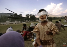 A girl, wounded in an earthquake and waiting to be airlifted to capital Islamabad for further treatment, weeps as she tries to avoid dust from a arriving helicopter at an army base in the northern Pakistani town of Muzaffarabad, Thursday, Oct. 13, 2005. (AP Photo/Lefteris Pitarakis)
