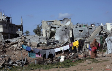 A Palestinian woman hangs washing next to the rubble of her destroyed house, in the Shijaiyah neighborhood of Gaza City, Monday, March 30, 2015. (AP Photo/Khalil Hamra)