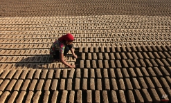 An Indian woman laborer works at an earthen brick factory on Earth Day on the outskirts of Jammu, India, Wednesday, April 22, 2015. The world marks Earth Day on April 22 to increase awareness and to promote practices for the sustainability and protection of the Earth's natural environment. (AP Photo/Channi Anand)