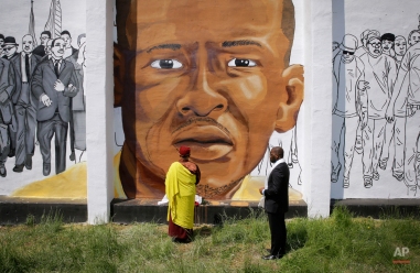 The Gyalwang Drukpa, bottom center, the Buddhist leader of South Asia, prays in front of a mural depicting Freddie Gray alongside the Rev. Jamal Bryant during a walking tour with other faith and community leaders, Thursday, May 7, 2015, in Baltimore. The group visited the site of Gray's arrest and a store that was damaged by fire during last month's unrest. (AP Photo/Patrick Semansky)