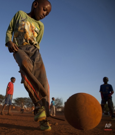 Young boys play soccer on a dusty field in Thokoza township east of Johannesburg, South Africa, Thursday, May 28, 2015. The image of South Africa's 2010 World Cup has been shattered by allegations that its bid over a decade ago was involved in bribes of more than $10 million to secure FIFA votes, possibly with the knowledge or involvement of the South African government. (AP Photo/Themba Hadebe)