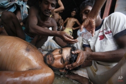 Newly arrived Bangladeshi migrants pour water on the head of a man who had fainted at Kuala Langsa Port in Langsa, Aceh province, Indonesia, Friday, May 15, 2015. Hundreds of Bangladeshi and ethnic Rohingya migrants have landed on the shores of Indonesia and Thailand after being adrift at sea for weeks, authorities said Friday. (AP Photo/Binsar Bakkara)