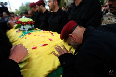 A Hezbollah fighter, right, mourns over the coffin of his comrade Ahmad al-Amin, who was killed while fighting in Qalamoun mountains against Nusra Front, al-Qaida's branch in Syria, during his funeral procession in the southern village of Babliyeh, Lebanon, Thursday, May 14, 2015. Syrian troops backed by Lebanese Hezbollah fighters have made progress in the Qalamoun mountains along Lebanon's border, near the Syrian capital. (AP Photo/Mohammed Zaatari)