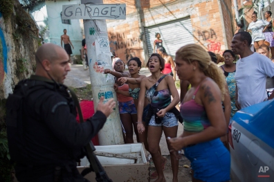 Residents shout at a Special Operations Battalion (BOPE) Police officer after the bodies of two men were found in the Sao Carlos slum complex in Rio de Janeiro, Brazil, Friday, May 15, 2015. The bodies of two young men were discovered late Thursday in this so-called "pacified" slum where police are present. The deaths come amid a turf war involving drug trafficking gangs that has killed at least 10 people in downtown slums in recent days. (AP Photo/Felipe Dana)