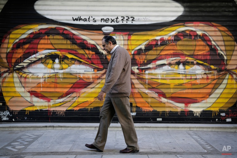 In this photo made on April 29, 2015, a Greek man walks past graffiti in central Athens. (AP Photo/Petros Giannakouris)