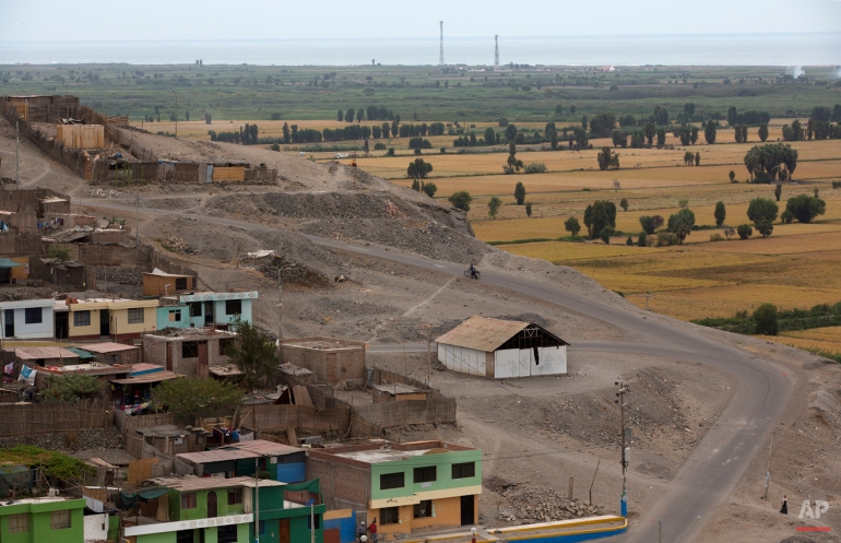 In this May 30, 2015 photo, a man walks with his bicycle through the poorer desert zone of Dean Valdivia, overlooking the rich farmland of the Tambo Valley, Arequipa, Peru. The company, Grupo Mexicano, suspended its $1.4 million copper mining project for 60 days last month in the fertile coastal valley of southern Peru where extraction project was met with two months of violent anti-mining protests. (AP Photo/Rodrigo Abd)
