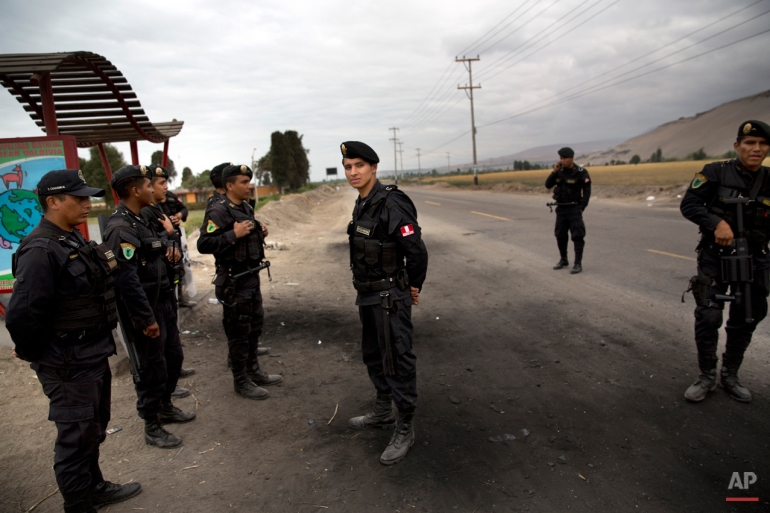 In this May 30, 2015 photo, riot policemen stand guard at the entrance of the Punta Bombon village in Tambo Valley, Arequipa, Peru. The government suspended civil liberties late last month in the valley where public assembly is illegal and security forces to search homes and make arrests without warrants. (AP Photo/Rodrigo Abd)