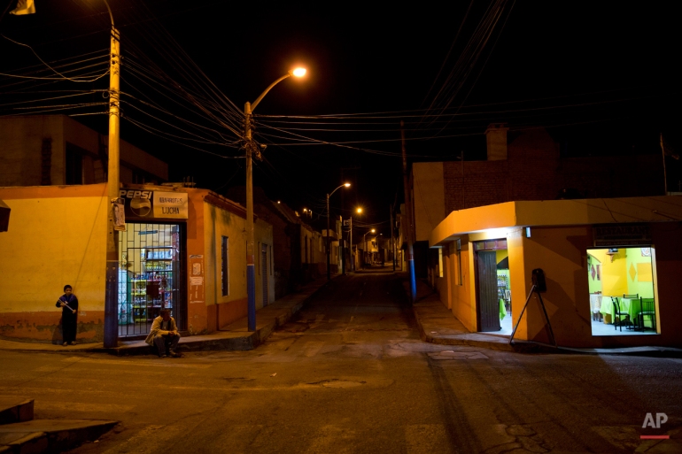 In this May 29, 2015 photo, two residents gather outside their homes, looking out at the empty streets in Cocachacra district in Tambo Valley, Arequipa, Peru. The government suspended civil liberties late last month in the valley as President Ollanta Humala sent in 2,000 soldiers to restore order in the valley, after nearly two months of violent anti-mining protests. Public assembly is illegal and security forces can search homes and make arrests without warrants. (AP Photo/Rodrigo Abd)