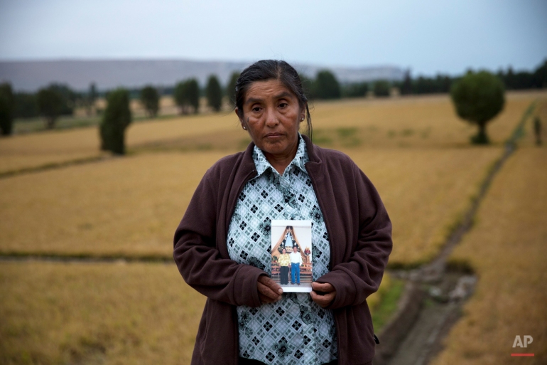 In this May 30, 2015 photo, Elena Lupez, 51, poses holding a photograph of herself and her late husband Ramon Colque, in Tambo Valley, Arequipa, Peru. Lopez says her husband lost his life during a violent protest against the mining project Tia Maria. She says he went to the protest to sell papa rellenas, and then joined in the protest. Lopez believes her 55-year-old husband died from a stray bullet shot by riot police, piercing his lung. (AP Photo/Rodrigo Abd)