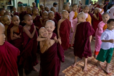 A novice Buddhist monk playfully holds another, as other novice monks, nuns and children gather for an assembly at the beginning of a school day at a monastic school in Yangon, Myanmar, Friday, June 12, 2015. Monastic schools, founded and run by the monks with a little support from the government, provide education for over 150,000 children. (AP Photo/Gemunu Amarasinghe)