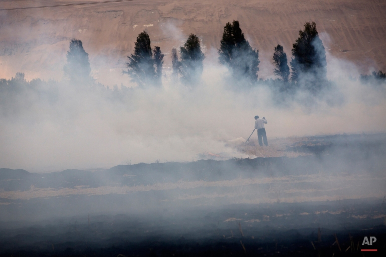In this May 30, 2015 photo, a man burns a pasture after the rice harvest, to ready the field for planting potatoes in Tambo Valley, Arequipa, Peru. Life is peaceful in the valley whose 47,000 residents are mostly farmers. (AP Photo/Rodrigo Abd)