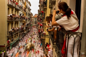 People watch as El Tajo y La Reina fighting bulls and revelers run during the running of the bulls, at the San Fermin festival, in Pamplona, Spain, Wednesday, July 8, 2015. Revelers from around the world arrive to Pamplona every year to take part in some of the eight days of the running of the bulls. (AP Photo/Andres Kudacki)