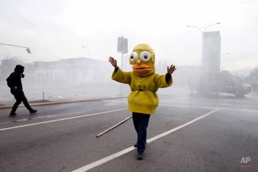 A protester dressed as the cartoon character Homer Simpson steps between demonstrators and police, in an attempt to stop clashes at the end of a student march in Santiago, Chile, Thursday, Aug. 27, 2015. Demonstrators came out to complain about delays in an education overhaul and ask President Michelle Bachelet to fulfill her campaign promise of free education. (AP Photo/Luis Hidalgo)