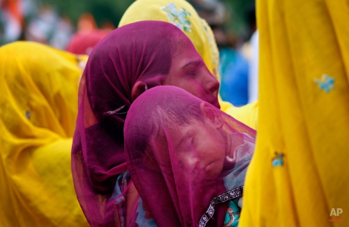 An Indian village woman covers a sleeping child with her veil as she carries him on her shoulder at Ajmer in India's Rajasthan state, Wednesday, Aug. 5, 2015. Married Hindu women in parts of Indian states observe a veil, or cover their heads as a long followed tradition. (AP Photo/Deepak Sharma)