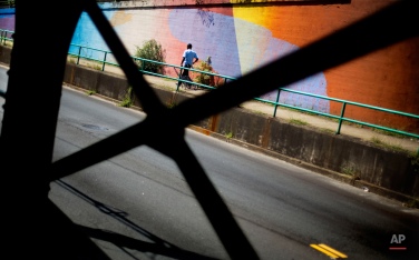 A pedestrian passes a mural along the Boulevard tunnel Tuesday, Aug. 25, 2015, in Atlanta. More than 1,000 feet of walls in the tunnel were painted last year in bright colors as part of an effort by Living Walls, an organization that brings artists together to create murals in the city's public spaces. (AP Photo/David Goldman)