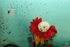 An artificial flower pot is seen next to a blood-stained wall at the home of blogger Niloy Chowdhury, who was hacked to death by unknown assailants in Dhaka, Bangladesh, Friday, Aug. 7, 2015. Assailants believed to be Islamist militants entered an apartment building posing as potential tenants and killed the secular blogger in Bangladesh's capital on Friday, the fourth such deadly attack this year, police said. (AP Photo/A.M. Ahad)