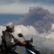 Motorists ride past as Mount Raung spews volcanic materials into the air in Melaten, East Java, Indonesia, Sunday, July 12, 2015. Ash spewing from the volcano on Indonesia's main island of Java sparked chaos for holidaymakers as airports closed and international airlines canceled flights. (AP Photo/Trisnadi)