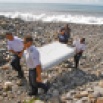 In this photo dated Wednesday, July 29, 2015, French police officers carry a piece of debris from a plane in Saint-Andre, Reunion Island. Air safety investigators, one of them a Boeing investigator, have identified the component as from the trailing edge of a Boeing 777 wing, a U.S. official said. Flight 370, which disappeared March 8, 2014, with 239 people on board, is the only 777 known to be missing. (AP Photo/Lucas Marie)