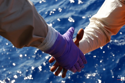 Migrants are helped to board on the Norwegian Siem Pilot ship during a migrant search and rescue mission off the Libyan Coasts, Tuesday, Sept. 1, 2015. Four dead bodies and hundreds of migrants were transferred on the Norwegian Siem Pilot ship from an Italian Navy ship and a Doctor Without Borders vessels after being rescued in different operation in the mediterranean sea. (AP Photo/Gregorio Borgia)