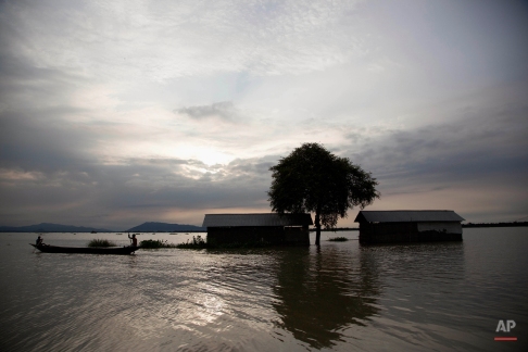A boat crosses houses partially submerged in floodwaters at Balimukh village, about 70 kilometers (43 miles) east of Gauhati, India, Tuesday, Sept. 1, 2015. Monsoon floods have inundated hundreds of villages across the northeast Indian state of Assam, killing several people and forcing some 800,000 people to leave their homes. (AP Photo/Anupam Nath)