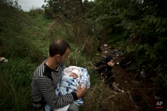 Syrian refugee Raed Alabdou, 24, holds his one-month old daughter Roa'a, while he and his wife hide in a field not to be seen by Hungarian policemen, after they crossed the Serbian-Hungarian border near Roszke, southern Hungary, Friday, Sept. 11, 2015. EU officials and human rights groups say they've been disappointed by the animosity toward asylum-seekers in countries from which hundreds of thousands of people fled communist dictatorships just decades ago. (AP Photo/Muhammed Muheisen)