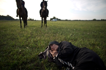An elderly Afghan migrant rests on the ground of a field while she and others being detained by Hungarian police on horses for sneaking through Hungary's border fence with Serbia, in Asotthalom, southern Hungary, Wednesday, Sept. 16, 2015. Small groups of migrants are continuing to sneak into Hungary from Serbia, a day after the country sealed its border and began arresting asylum-seekers trying to breach the new razor-wire barrier. (AP Photo/Muhammed Muheisen)