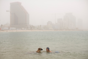 An Israeli man and his dog bathe in the Mediterranean Sea along the beach front during a sandstorm in Tel Aviv, Israel, Wednesday, Sept. 9, 2015. The unseasonal sandstorm has swept across the Mideast, blanketing Beirut, Cairo and Damascus. In Egypt, the state news agency said authorities have closed four ports in the Suez governorate because of poor visibility due to a sandstorm gripping the Middle East. (AP Photo/Oded Balilty)
