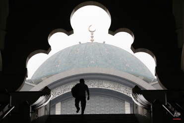 A Malaysian Muslim man is silhouetted against the Wilayah Mosque shrouded with haze in Kuala Lumpur, Malaysia, Monday, Oct. 19, 2015. Malaysian authorities ordered school closure again due to the haze situation. (AP Photo/Joshua Paul)