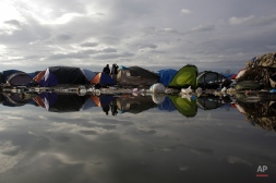 Tents are reflected in a puddle with waste inside the camp known as the Jungle in Calais, northern France, Tuesday, Nov. 3, 2015. More than 5000 migrants are fleeing conflict zones or poverty at the rapidly growing camp outside Calais. All hope to make it across the English Channel to Britain. (AP Photo/Markus Schreiber)