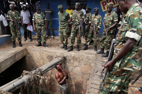 Jean Claude Niyonzima, a suspected member of the ruling party's Imbonerakure youth militia, pleads with soldiers to protect him from a mob of demonstrators after he came out of hiding in a sewer in the Cibitoke district of Bujumbura, Burundi, Thursday May 7, 2015. Niyonzima fled from his house into the sewer under a hail of stones thrown by a mob protesting President Pierre Nkurunziza's decision to seek a third term in office. (AP Photo/Jerome Delay)
