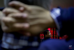 A man chats with other investors near an electronic board displaying stock prices at a brokerage house in Beijing, Tuesday, Jan. 19, 2016. Chinese shares were buoyed but the rest of Asian stock markets were largely flat Tuesday after China's quarterly economic growth met expectations, calming some of the investor jitters in the region. (AP Photo/Andy Wong)