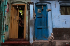 A Bangladeshi woman cleans the doorway to her home as a cat sits nearby early in the morning in Dhaka, Bangladesh, Thursday, Jan. 21, 2016. (AP Photo/A.M. Ahad)