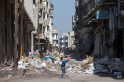 A Syrian boy plays between destroyed buildings in the old city of Homs, Syria, Friday, Feb. 26, 2016. The U.N. Security Council is expected to vote Friday afternoon on a draft resolution endorsing the "cessation of hostilities" in Syria that is set to start at midnight local time. The draft, obtained by The Associated Press, also urges the U.N. secretary-general to resume Syria peace talks "as soon as possible."(AP Photo/Hassan Ammar)